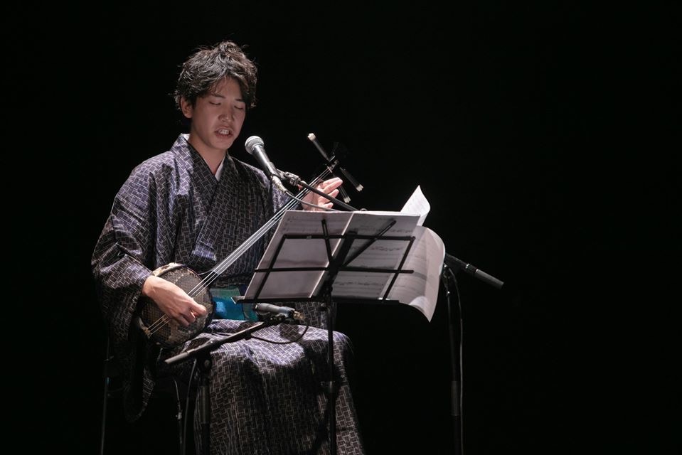 舞台で歌三線を演奏する仲嶺良盛